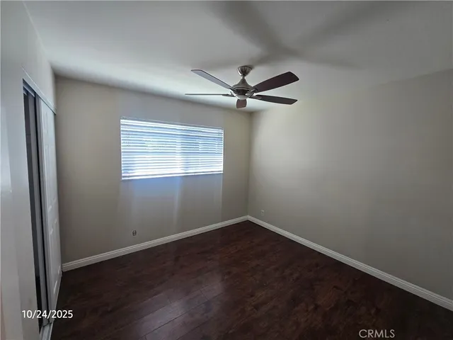 an empty room with wooden floor fan and windows