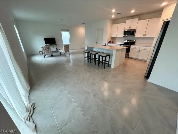 a view of kitchen with kitchen island stainless steel appliances refrigerator stove microwave and furniture