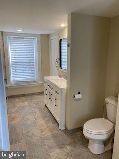 278 A Newtown Road Warminster, PA 18974 - Photo 10 of 21 a bathroom with a granite countertop toilet a sink a mirror and a window