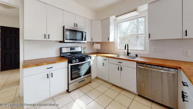 a kitchen with white cabinets appliances and a window