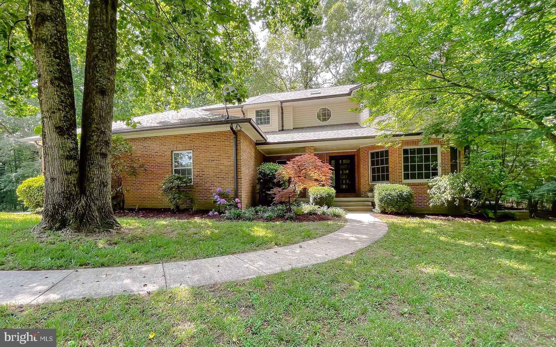 a view of a white house next to a yard with big trees