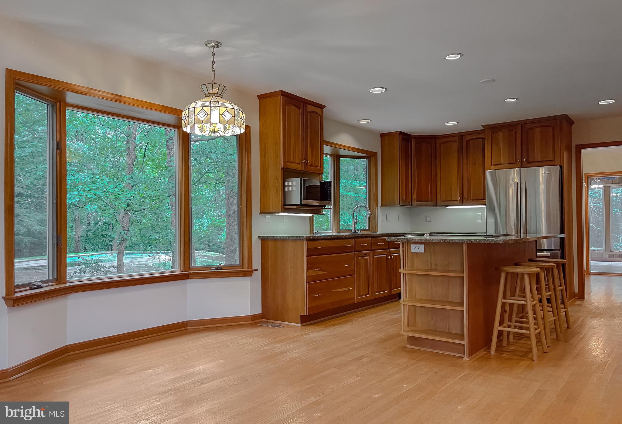 3050 Ross Road St. Leonard, MD 20685 - Photo 26 of 87 a kitchen with kitchen island granite countertop wooden cabinets a refrigerator a stove and a wooden floors