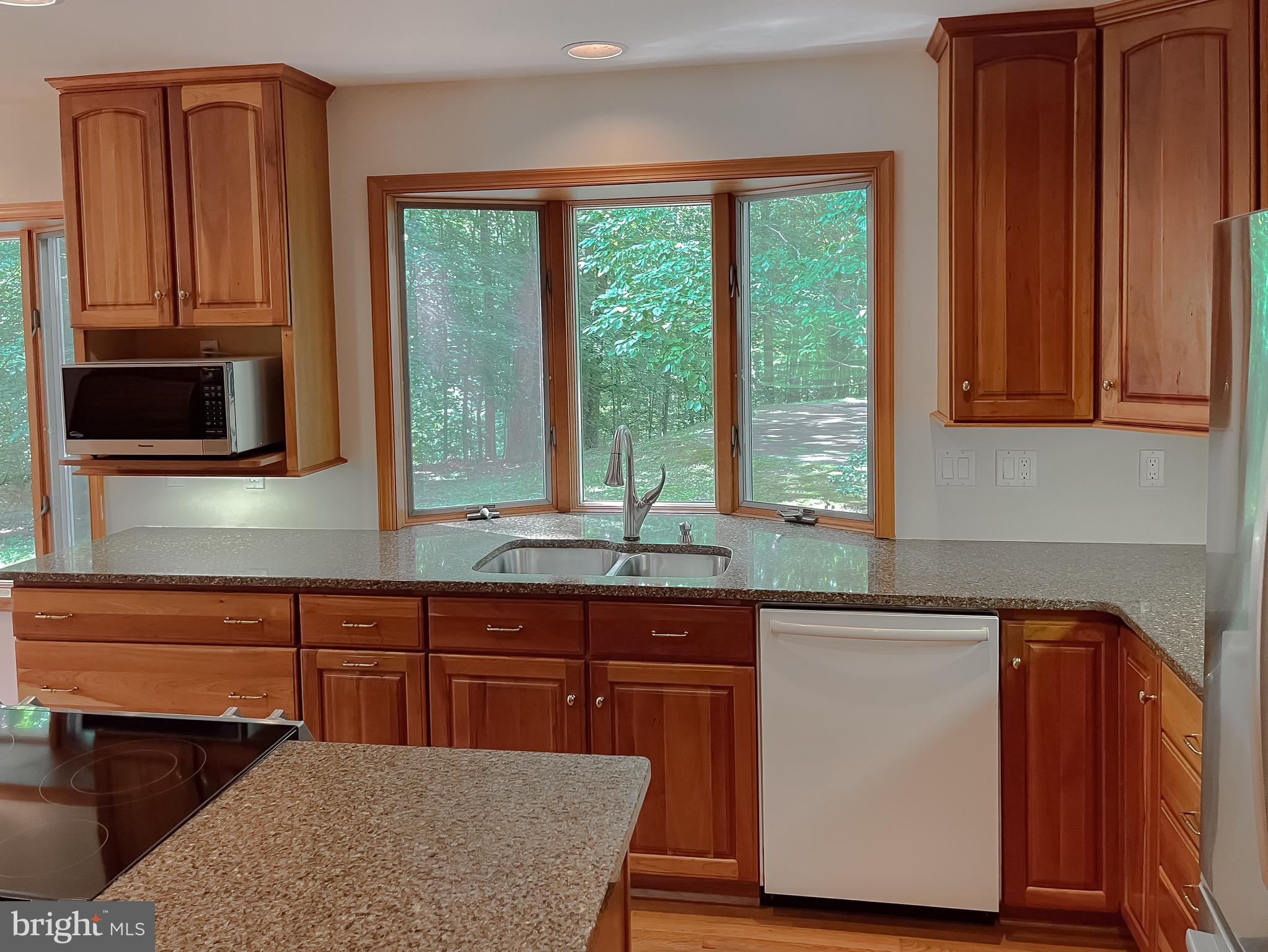 3050 Ross Road St. Leonard, MD 20685 - Photo 29 of 87 a kitchen with stainless steel appliances granite countertop wooden cabinets a sink and a microwave