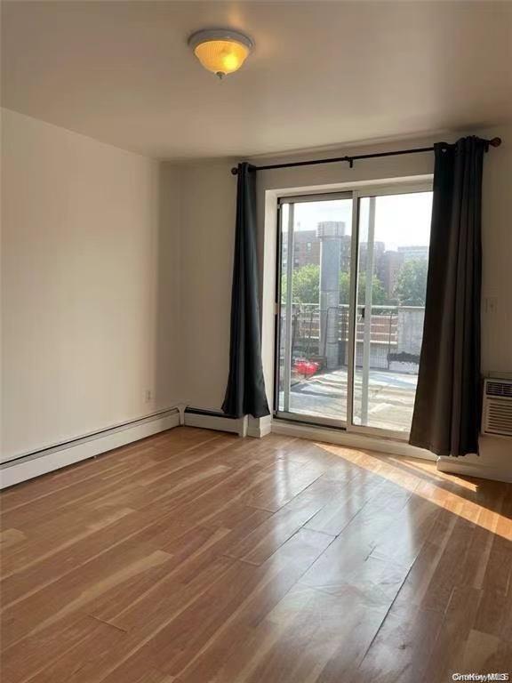 132-73 Maple Avenue, Unit 4A Queens, NY 11355 - Photo 4 of 10 a view of an empty room with wooden floor and a window