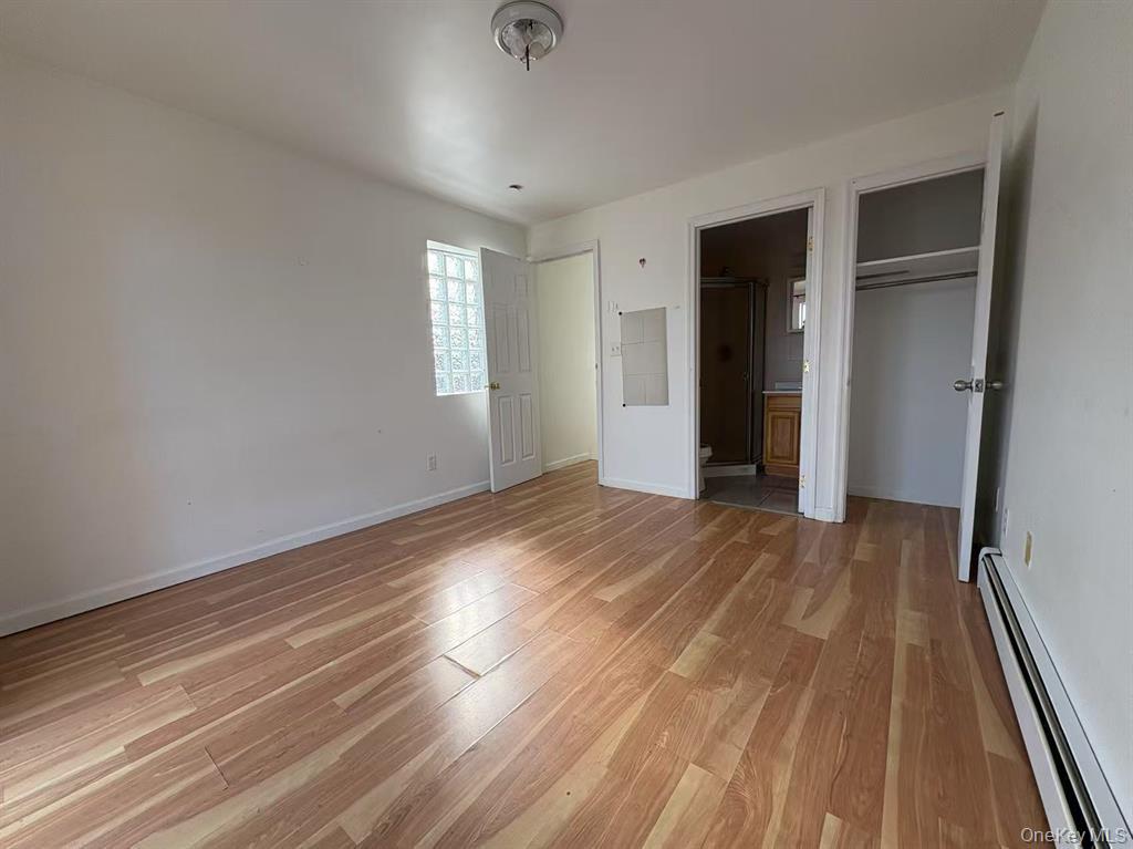 132-73 Maple Avenue, Unit 4A Queens, NY 11355 - Photo 5 of 10 an empty room with wooden floor and windows