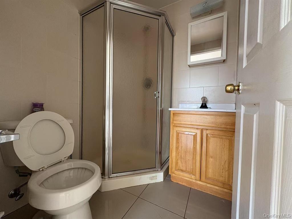 132-73 Maple Avenue, Unit 4A Queens, NY 11355 - Photo 9 of 10 a bathroom with a granite countertop toilet sink and mirror