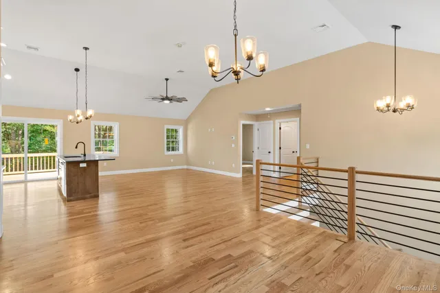 an empty room with wooden floor chandelier fan and windows