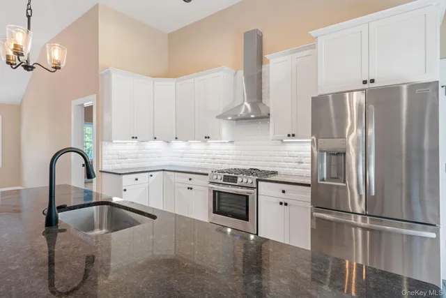 a kitchen with stainless steel appliances granite countertop a sink a refrigerator and a stove