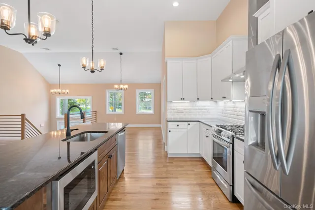 a kitchen with stainless steel appliances granite countertop a sink a stove and a refrigerator