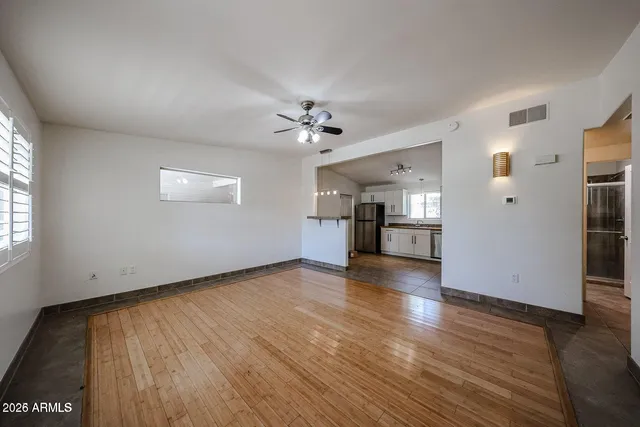 a view of an empty room with window and wooden floor