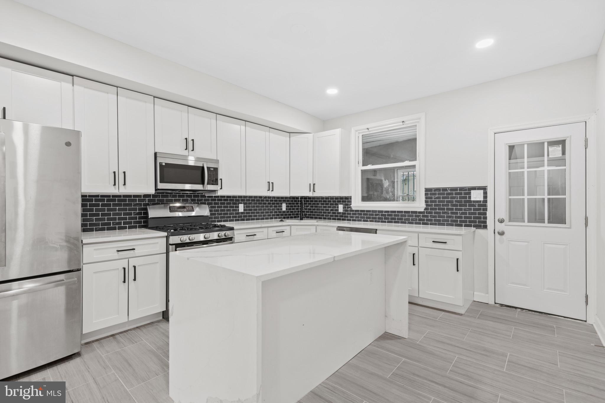 3404 East Pratt Street Baltimore, MD 21224 - Photo 14 of 39 a kitchen with stainless steel appliances granite countertop a stove a sink dishwasher a refrigerator and white cabinets with wooden floor