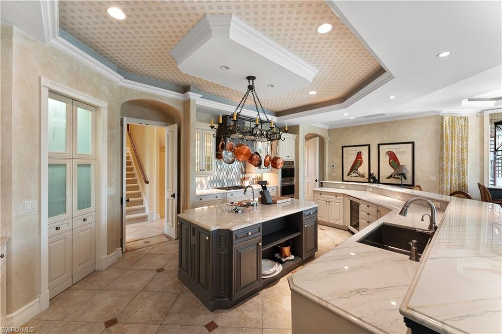 590 17th Avenue South Naples, FL 34102 - Photo 13 of 50 a kitchen that has a sink a stove top oven a dining table and chairs in it