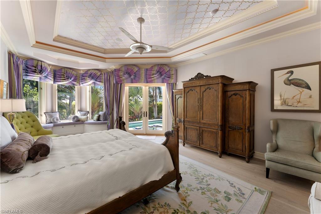 590 17th Avenue South Naples, FL 34102 - Photo 22 of 50 a spacious bedroom with a bed a couch and a chandelier