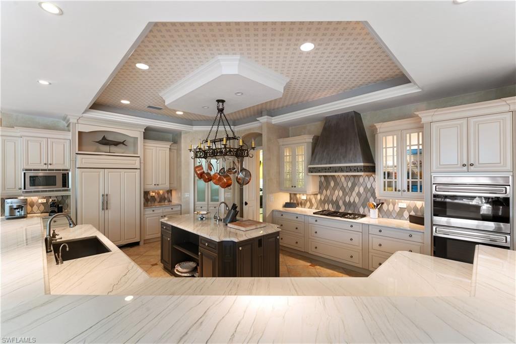 590 17th Avenue South Naples, FL 34102 - Photo 10 of 50 a kitchen with stainless steel appliances kitchen island granite countertop a sink counter space cabinets and a couch