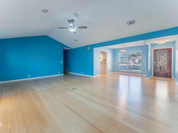 a view of an empty room with window and wooden floor