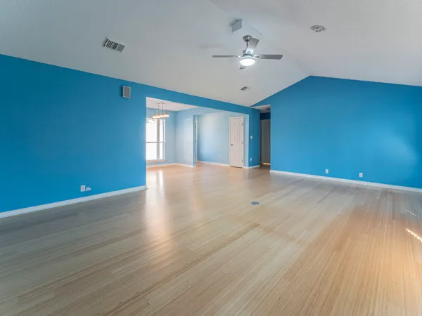 a view of an empty room with window and wooden floor