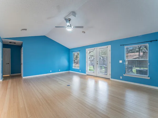 a view of an empty room with a window and wooden floor