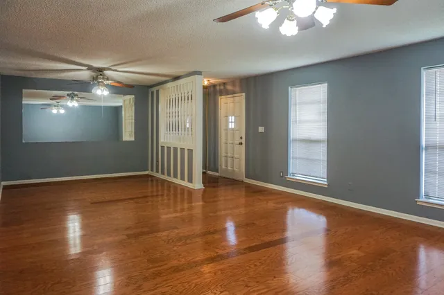 a view of an empty room with wooden floor and a window
