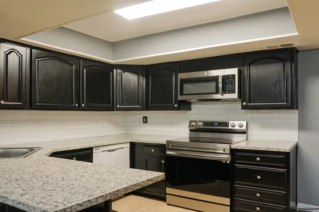 a kitchen with stainless steel appliances wooden cabinets a stove a microwave and a sink
