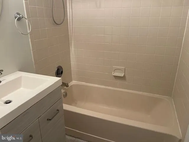 a white bath tub sitting next to a white sink and vanity