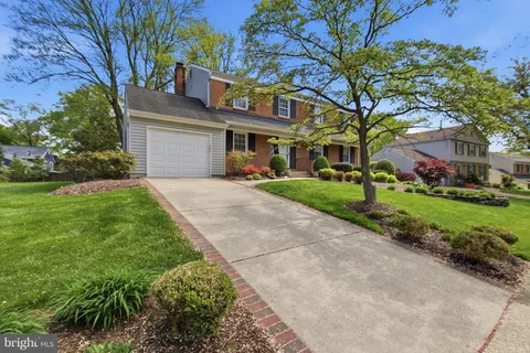 a front view of a building with a garden and trees