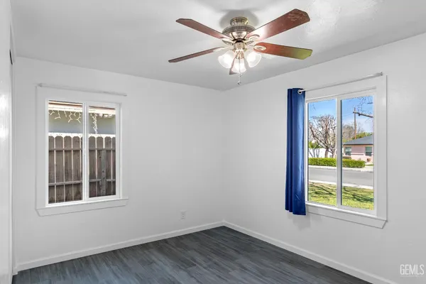 an empty room with windows and fan