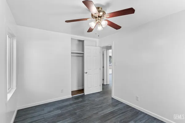 an empty room with wooden floor fan and windows