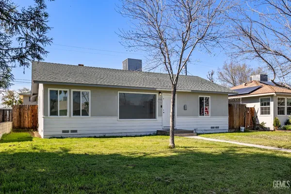 a view of a house with large windows and a yard with palm trees