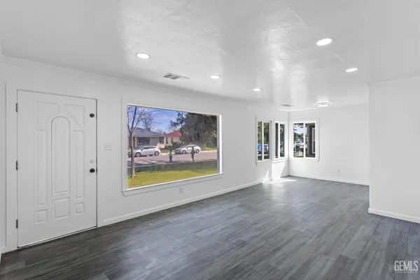 a view of an empty room with wooden floor and a painting on the wall