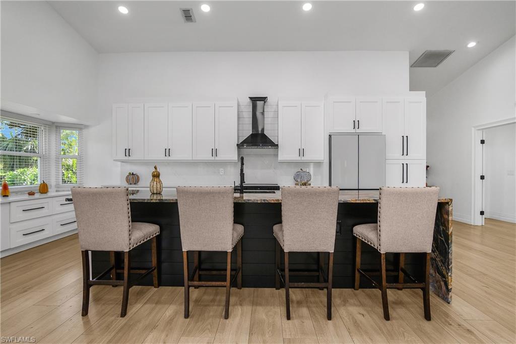 401 Countryside Drive Naples, FL 34104 - Photo 11 of 30 a kitchen with stainless steel appliances kitchen island granite countertop a dining table chairs and a refrigerator
