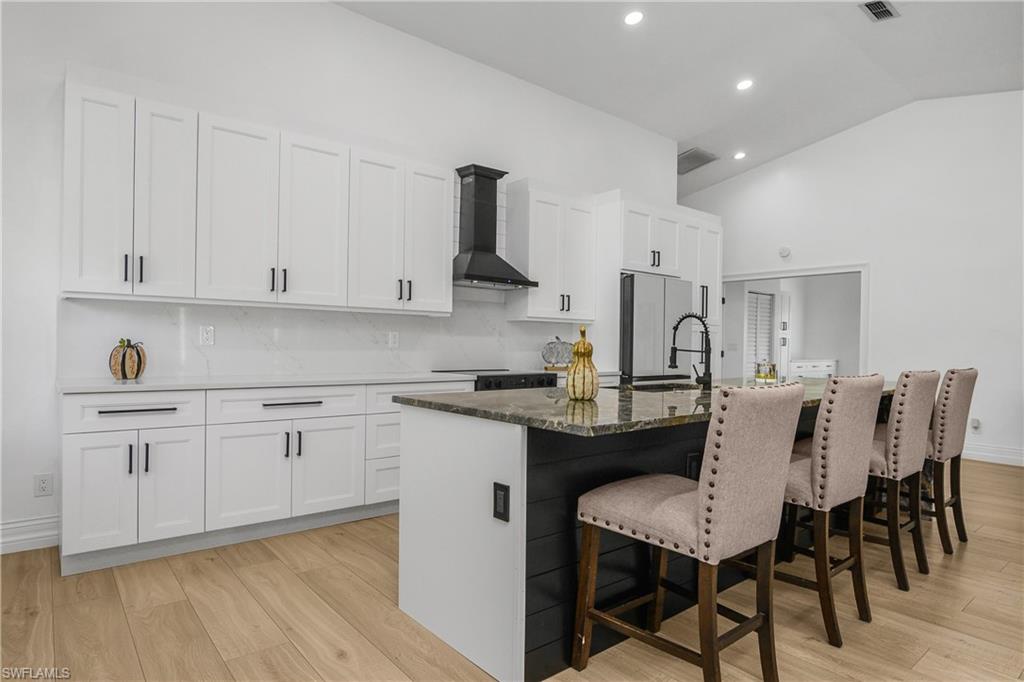 401 Countryside Drive Naples, FL 34104 - Photo 12 of 30 a kitchen with stainless steel appliances granite countertop a white cabinets and wooden floor