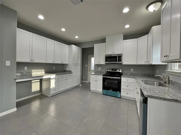 a large kitchen with granite countertop lots of white cabinets