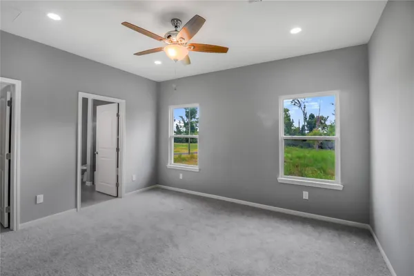 an empty room with windows and fan