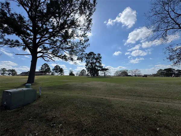 a view of a golf course with huge green field and covered with trees
