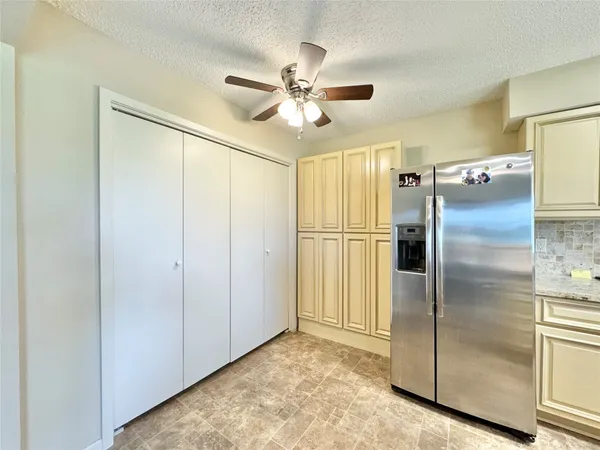 a view of a refrigerator in kitchen and an empty room