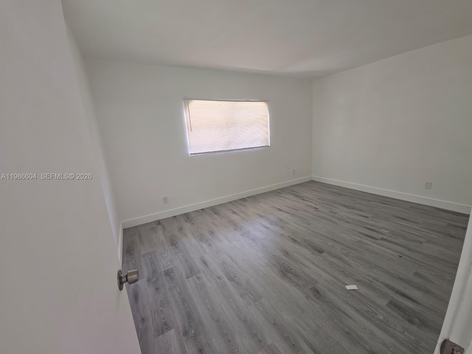 11287 Southwest 169th Street, Unit V41032 Miami, FL 33157 - Photo 11 of 14 an empty room with wooden floor and windows