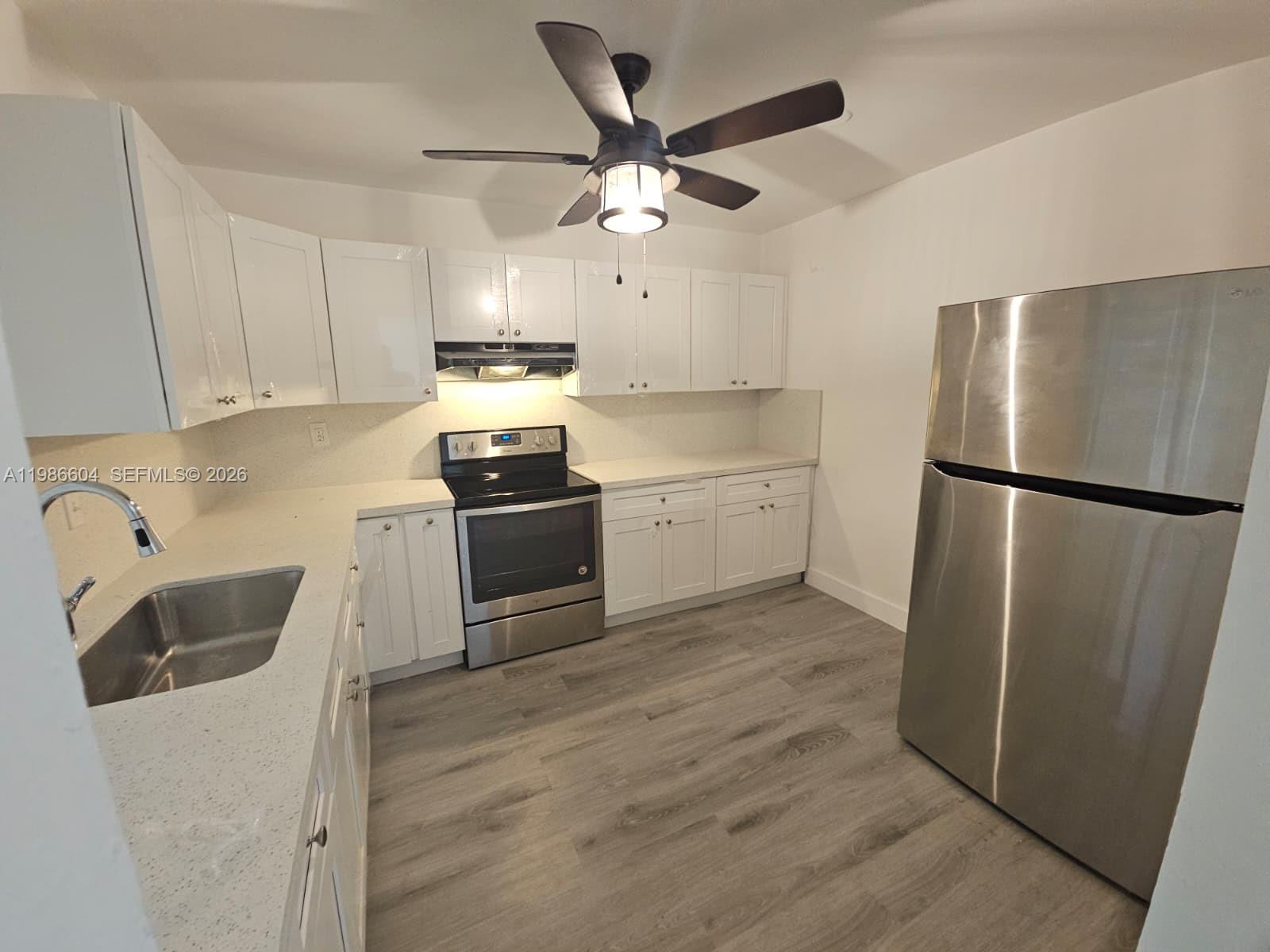 11287 Southwest 169th Street, Unit V41032 Miami, FL 33157 - Photo 6 of 14 a kitchen with a refrigerator sink and cabinets
