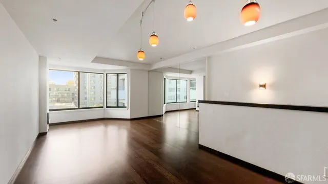 a view of an empty room with window and wooden floor