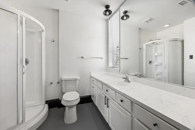 a spacious bathroom with a double vanity sink toilet mirror and shower