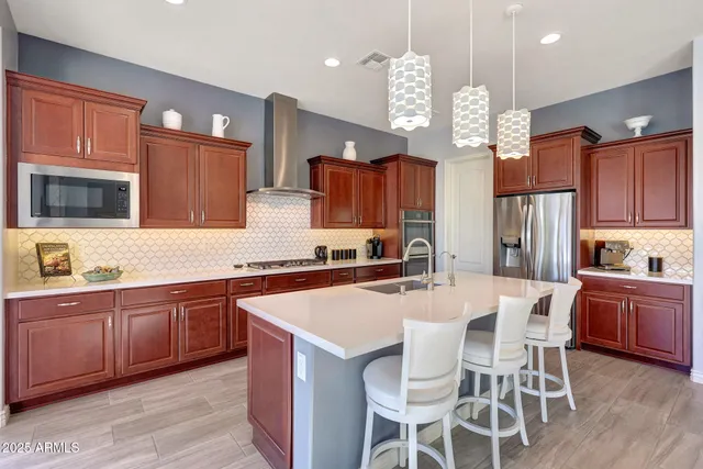 a kitchen with stainless steel appliances kitchen island granite countertop a stove top oven a sink dishwasher a dining table and chairs with wooden floor