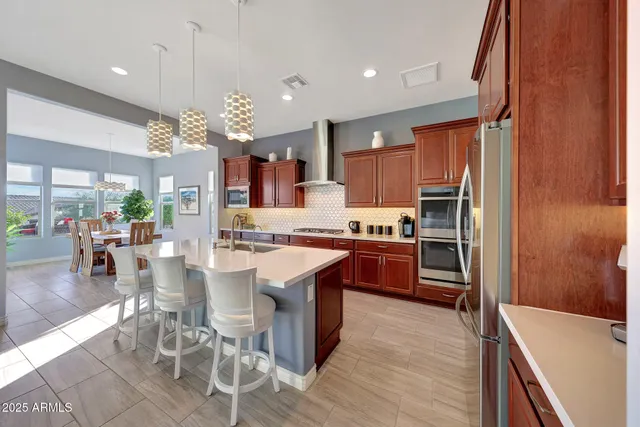 a kitchen with stainless steel appliances granite countertop a refrigerator a stove and a sink