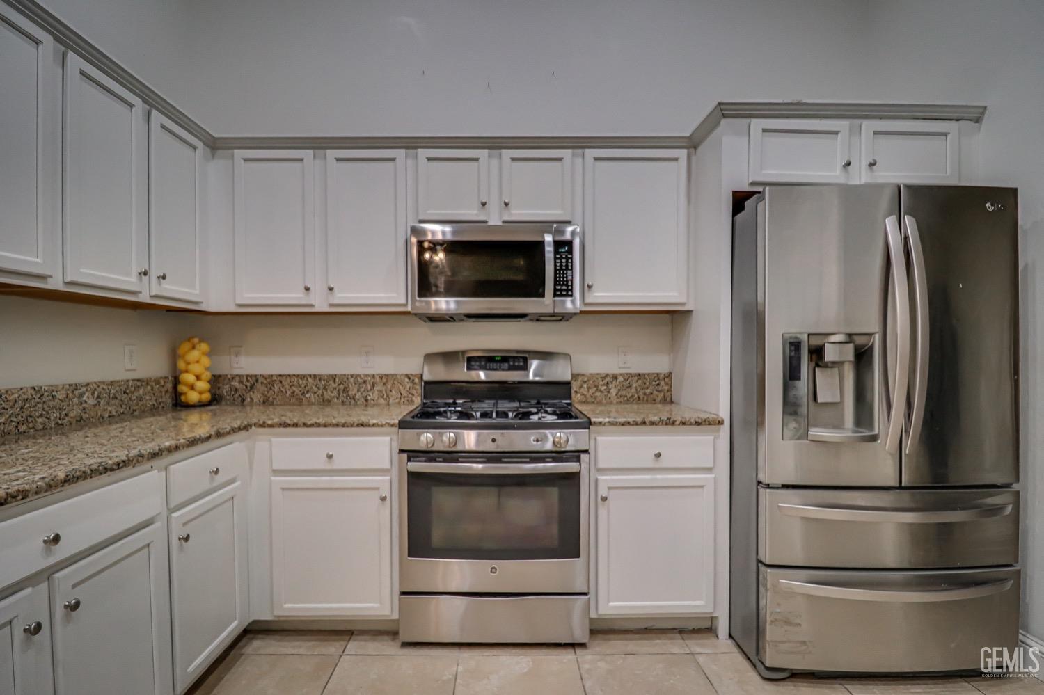 Undisclosed Address Bakersfield, CA 93313 - Photo 13 of 25 a kitchen with white cabinets and stainless steel appliances