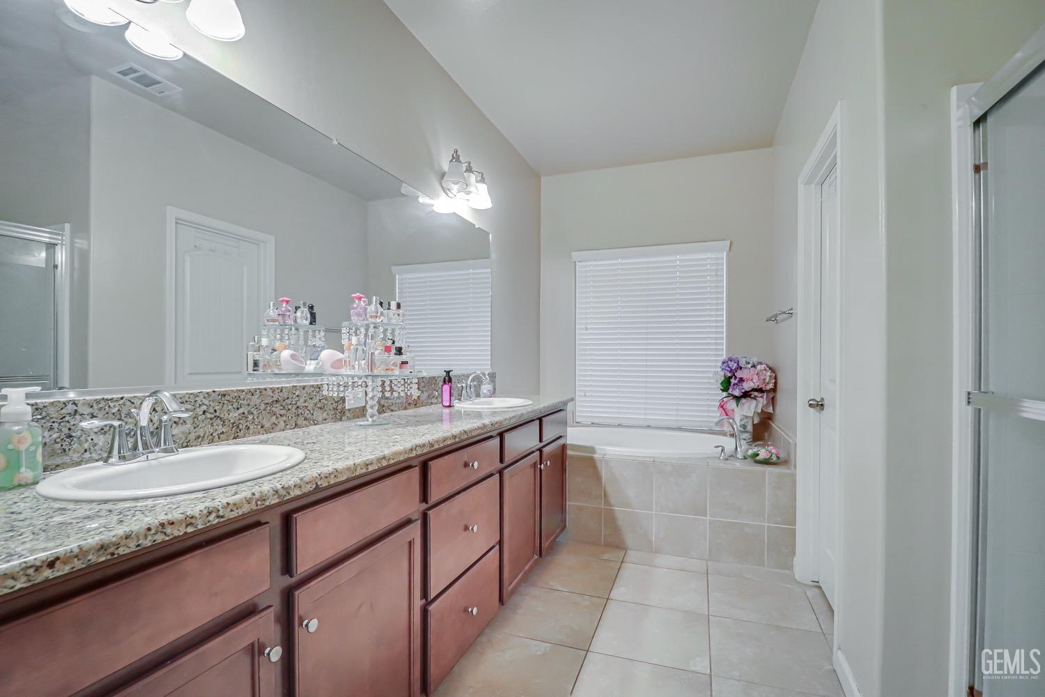 Undisclosed Address Bakersfield, CA 93313 - Photo 20 of 25 a bathroom with a granite countertop sink a mirror and a bathtub