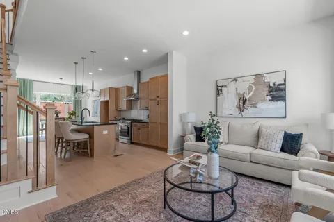 a living room with furniture potted plant and kitchen view