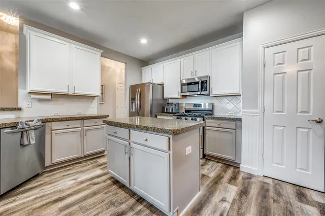 a kitchen with granite countertop white cabinets and stainless steel appliances