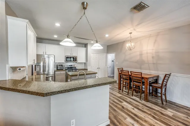 a kitchen with stainless steel appliances granite countertop a sink a stove and a table