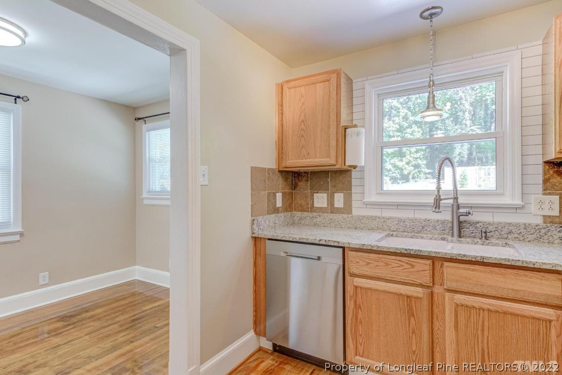 2710 Broad Street Durham, NC 27704 - Photo 20 of 36 a kitchen with granite countertop white cabinets and a window