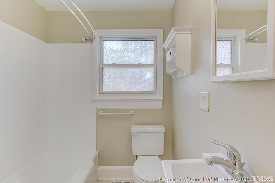 2710 Broad Street Durham, NC 27704 - Photo 22 of 36 a white toilet sitting next to a bathroom sink and a window