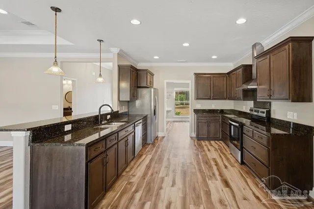 a kitchen with stainless steel appliances kitchen island granite countertop a stove a sink and a refrigerator