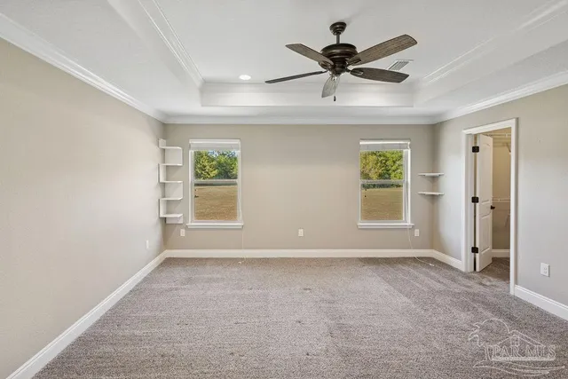 an empty room with ceiling fan and windows
